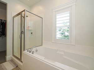 Full bathroom with a stall shower, a garden tub, and a spacious closet
