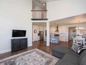 Living area with dark wood finished floors, a chandelier, baseboards, and ornate columns