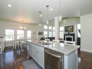 Kitchen with stainless steel dishwasher, a sink, baseboards, a chandelier, and recessed lighting
