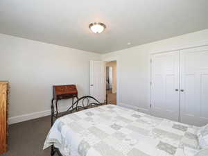 Bedroom featuring dark carpet, baseboards, and a closet