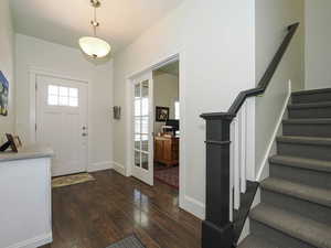 Entrance foyer with dark wood-style floors, stairway, and baseboards