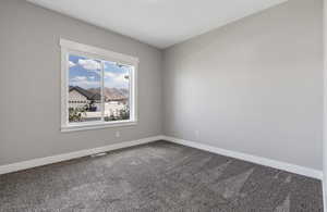 Spare room featuring dark carpet and baseboards