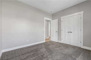 Unfurnished bedroom with carpet flooring, baseboards, and a closet