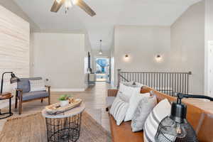 Sitting room with wood finished floors, ceiling fan, and vaulted ceiling