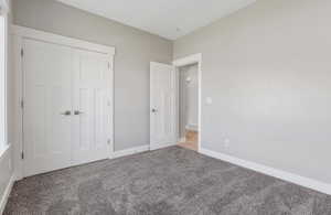 Unfurnished bedroom with carpet floors, a closet, and baseboards