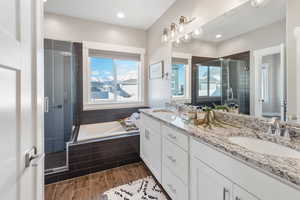 Full bathroom featuring a stall shower, a garden tub, double vanity, wood finished floors, and recessed lighting