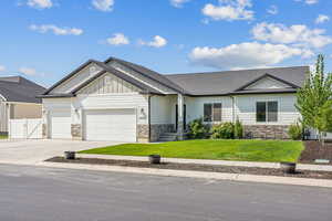 View of front facade with stone siding, an attached garage, concrete driveway, and board and batten siding