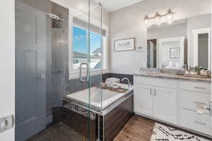 Bathroom with a shower stall, a bath, and vanity