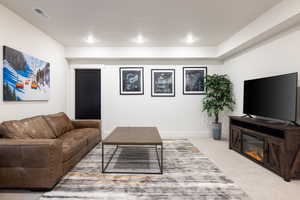 Living room with light colored carpet, recessed lighting, and baseboards