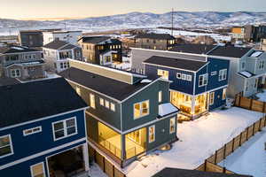 Snowy aerial view featuring a mountain view and a residential view