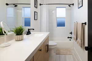 Bathroom with shower / bathtub combination with curtain, toilet, and vanity