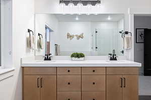 Bathroom featuring a shower stall and double vanity