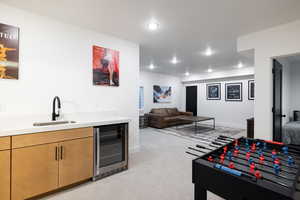 Bar area featuring a sink, beverage cooler, light carpet, recessed lighting, and baseboards
