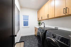 Laundry room featuring separate washer and dryer, cabinet space, baseboards, and dark tile patterned flooring