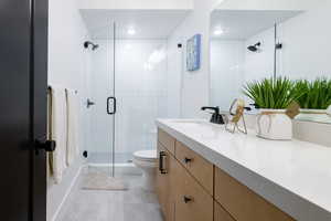 Bathroom featuring vanity, a shower stall, toilet, tile patterned flooring, and recessed lighting