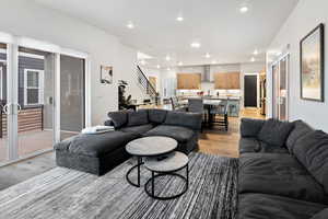 Living area with light wood finished floors and recessed lighting
