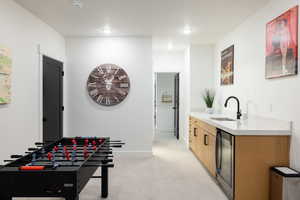 Playroom with a sink, beverage cooler, light carpet, baseboards, and recessed lighting