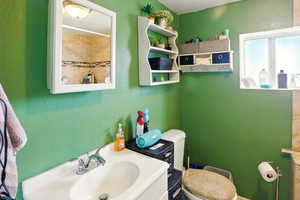 Bathroom featuring toilet, a sink, and a textured wall