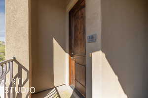 Property entrance with stucco siding and a balcony