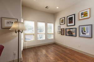 Empty room with dark wood finished floors, a textured wall, and recessed lighting