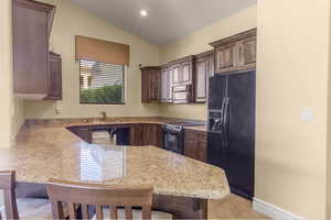 Kitchen with a kitchen breakfast bar, black appliances, a peninsula, dark brown cabinets, and light tile patterned floors