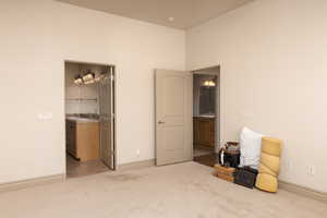 Bedroom with light colored carpet and connected bathroom