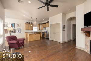 Living room featuring arched walkways, ceiling fan, dark wood-style flooring, a fireplace, and recessed lighting