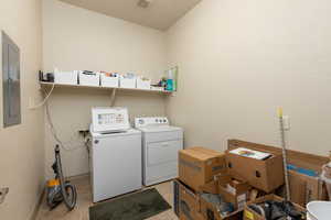 Laundry room featuring electric panel, independent washer and dryer, and light tile patterned floors