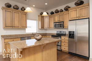 Kitchen featuring appliances with stainless steel finishes, dark wood-style floors, a kitchen island, a breakfast bar, and recessed lighting