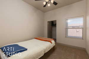 Carpeted bedroom featuring a spacious closet, a closet, a ceiling fan, and baseboards