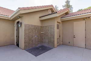 View of exterior entry featuring stucco siding, a patio area, and a tile roof