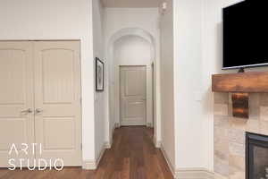 Hallway with arched walkways, wood finished floors, and baseboards