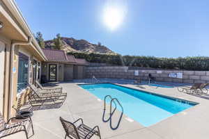 Community pool featuring a mountain view, a fenced backyard, and a patio area