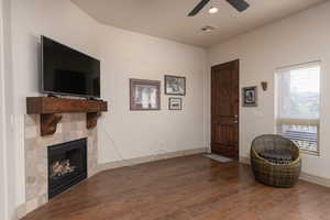 Living area featuring dark wood-type flooring, a tiled fireplace, recessed lighting, and ceiling fan