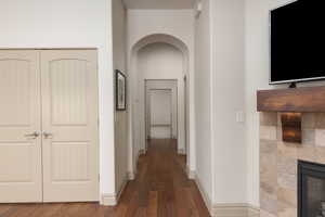 Corridor featuring arched walkways and dark wood-style flooring