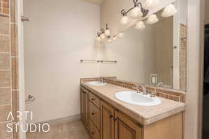 Full bathroom with tile patterned flooring, double vanity, baseboards, and a chandelier