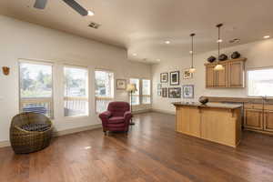 Kitchen featuring a breakfast bar, open floor plan, a kitchen island, pendant lighting, and dark wood finished floors