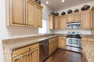 Kitchen with stainless steel appliances, a sink, dark wood finished floors, recessed lighting, and light stone countertops