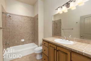 Bathroom with toilet, tile patterned flooring,  shower combination, and vanity