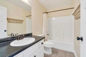 Full bath with toilet, tile patterned floors, shower / bath combo, and vanity