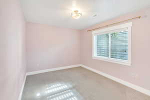 Carpeted empty room featuring baseboards and a textured ceiling