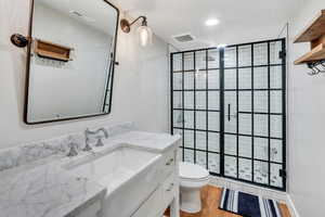 Full bath with a shower stall, toilet, vanity, and wood finished floors