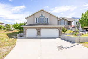 View of front facade with an attached garage, driveway, stucco siding, and brick siding