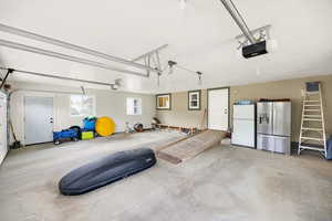 Garage featuring freestanding refrigerator, stainless steel fridge, and a garage door opener