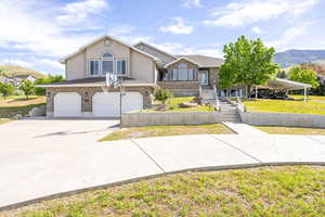 Multi unit property with a garage, driveway, stucco siding, and a front yard