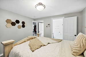 Bedroom featuring ensuite bathroom, a spacious closet, a textured ceiling, baseboards, and a closet