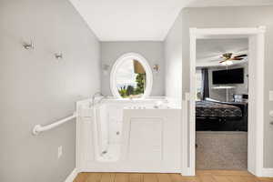 Bathroom with plenty of natural light, a ceiling fan, a whirlpool tub, and baseboards