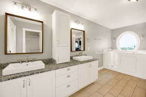 Bathroom featuring double vanity, baseboards, and a bathtub