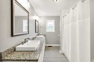 Full bathroom featuring double vanity and baseboards