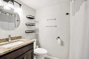 Bathroom with toilet, vanity, and curtained shower